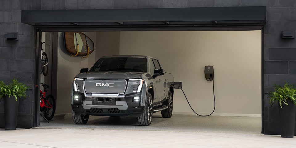A GMC Sierra EV Parked Inside a Garage Plugged Into a Charging Unit